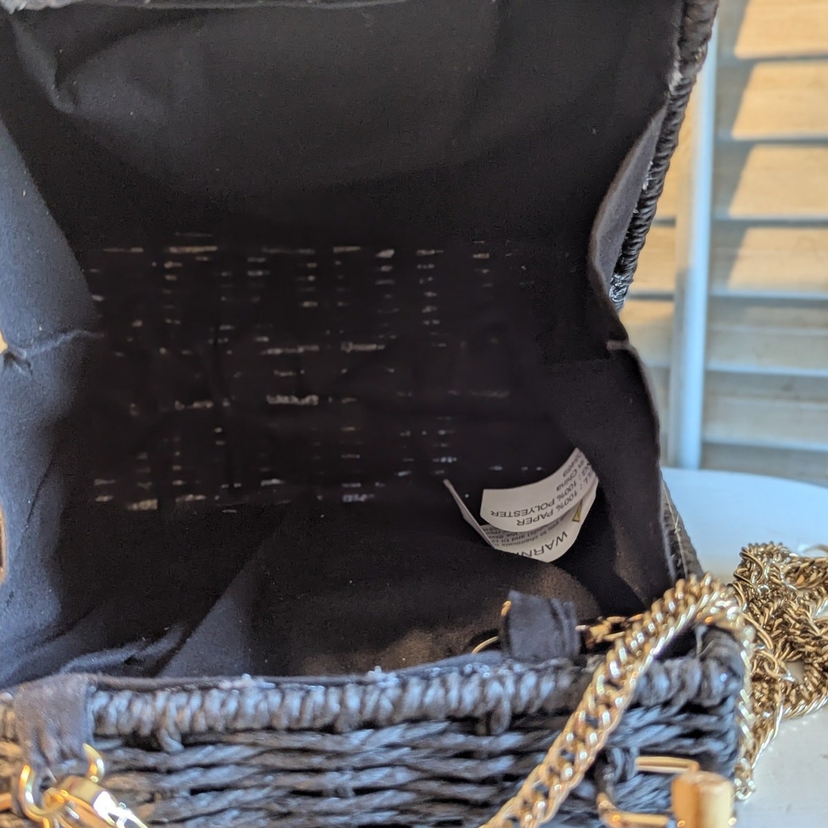 Black woven handbag with bamboo handle and gold chain strap